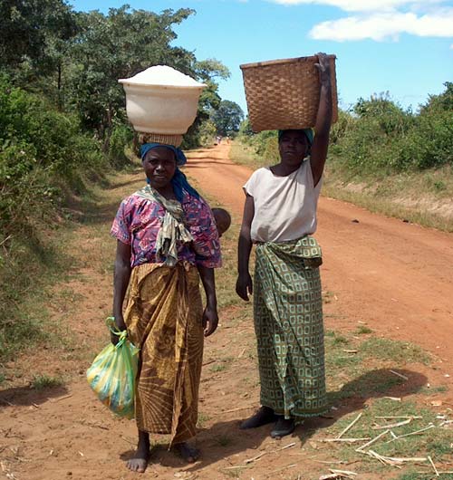 African Women Carrying Children and Loads Along Road, 